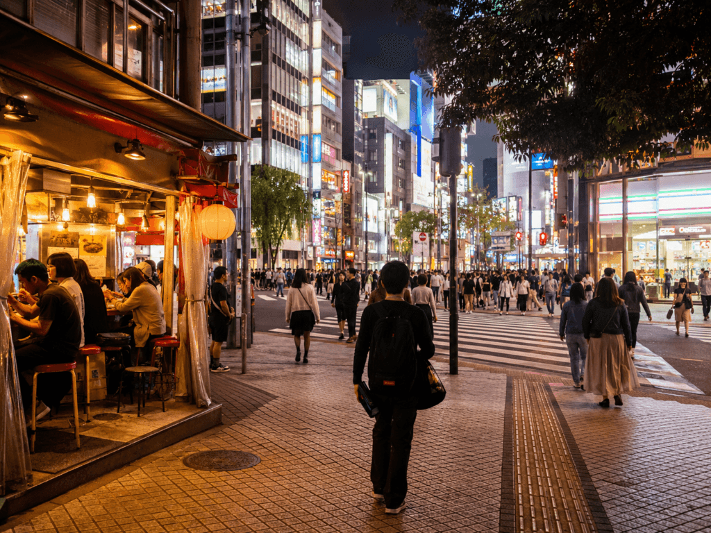 Tokyo night street scene with neon lights, ramen shop, busy crosswalk, travelers and warm city energy