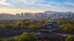 Traditional Korean palace rooftops with the modern Seoul skyline and mountains in the distance