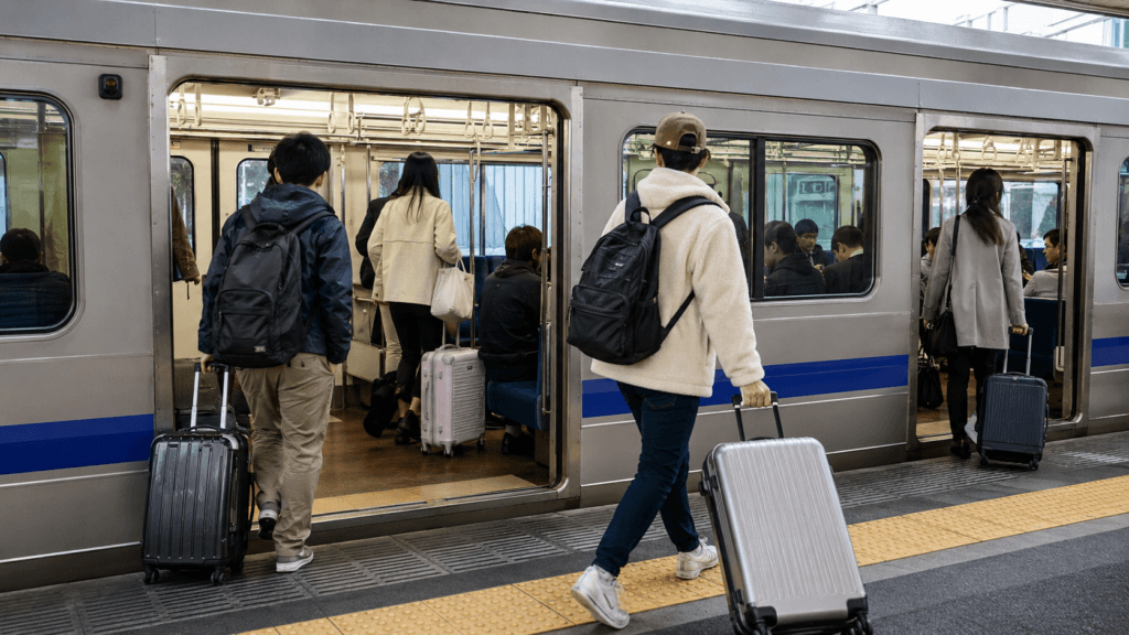Travelers boarding a commuter train with suitcases at Narita Airport