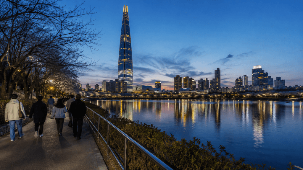 Visitors walking beside Seokchon Lake and Lotte World Tower at night