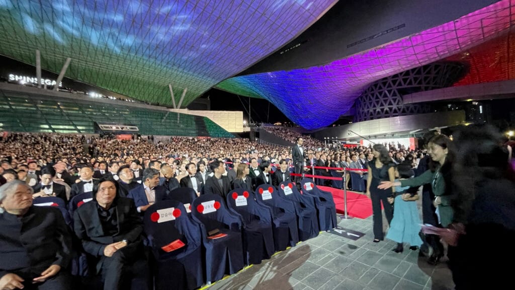 Audience seated beneath the illuminated Busan Cinema Center roof on BIFF 2023 opening night
