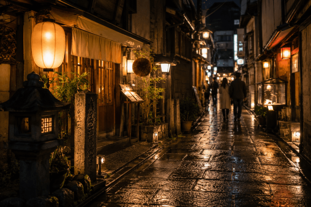 Quiet traditional alley near Dotonbori at night with warm lantern light, wet stone pavement and travelers walking in the distance