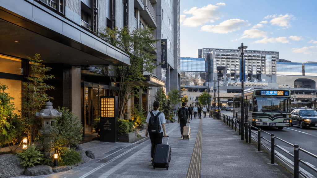 Modern hotel street near Kyoto Station with travelers carrying luggage and urban transport nearby