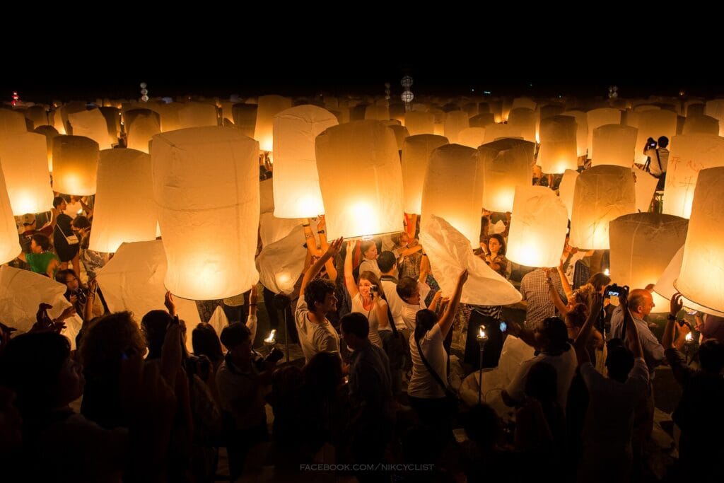 People holding illuminated sky lanterns during Yi Peng in Chiang Mai in 2013