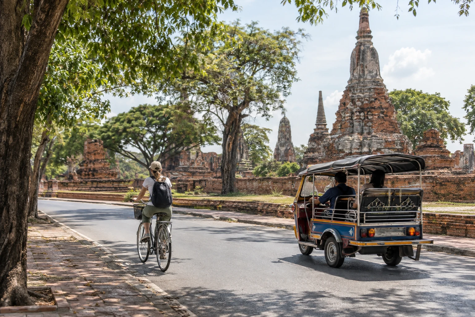 Traveler cycling beside an Ayutthaya tuk-tuk and red-brick temple ruins
